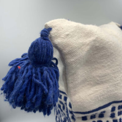 Détail pompon bleu en laine sur housse de coussin marocaine blanche – tissage berbère artisanal – Collection Tazra – KanelDéco